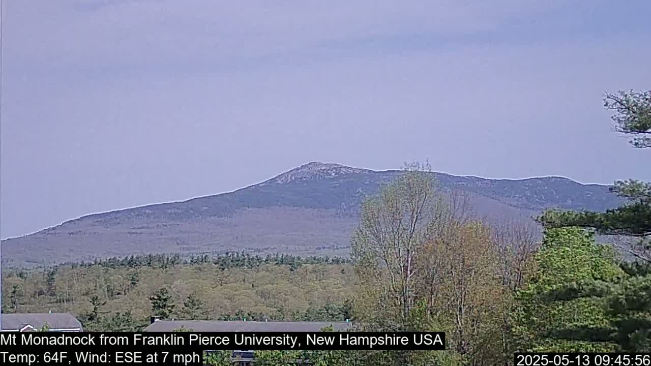 A distant, tree-covered mountain is visible under a hazy, light-blue sky.