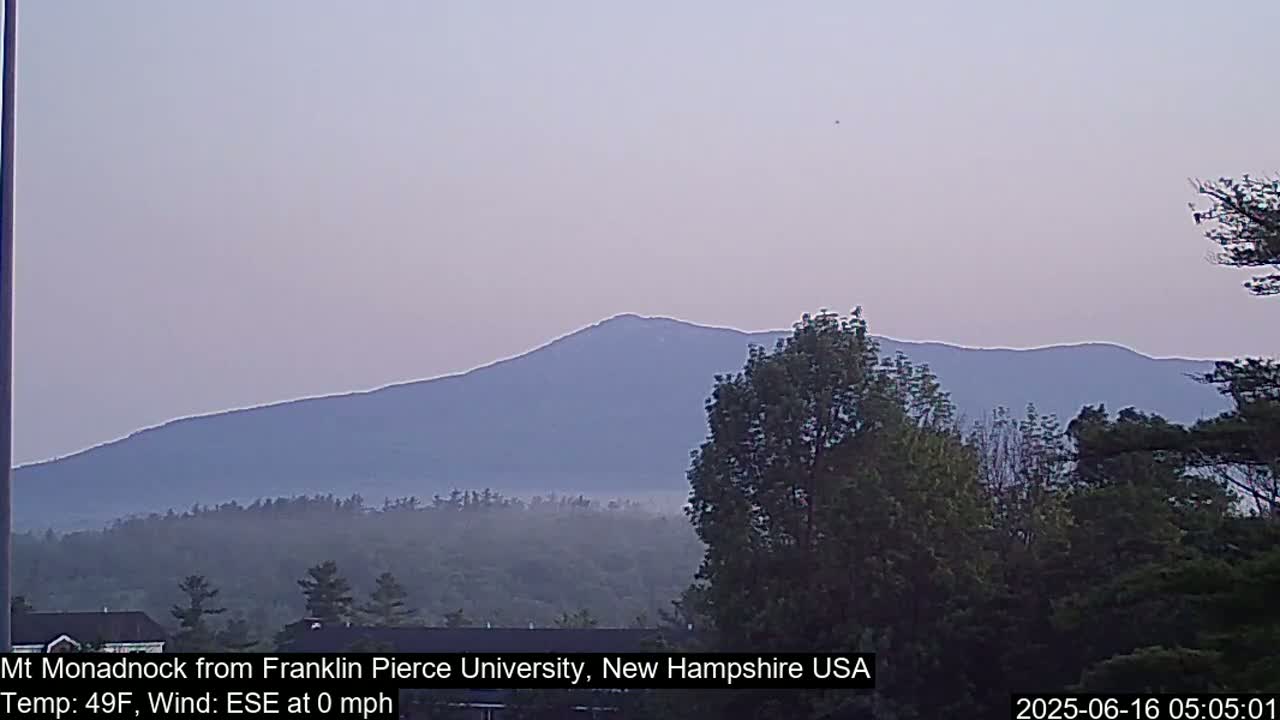 A hazy, calm morning reveals a distant mountain range under a pale sky.