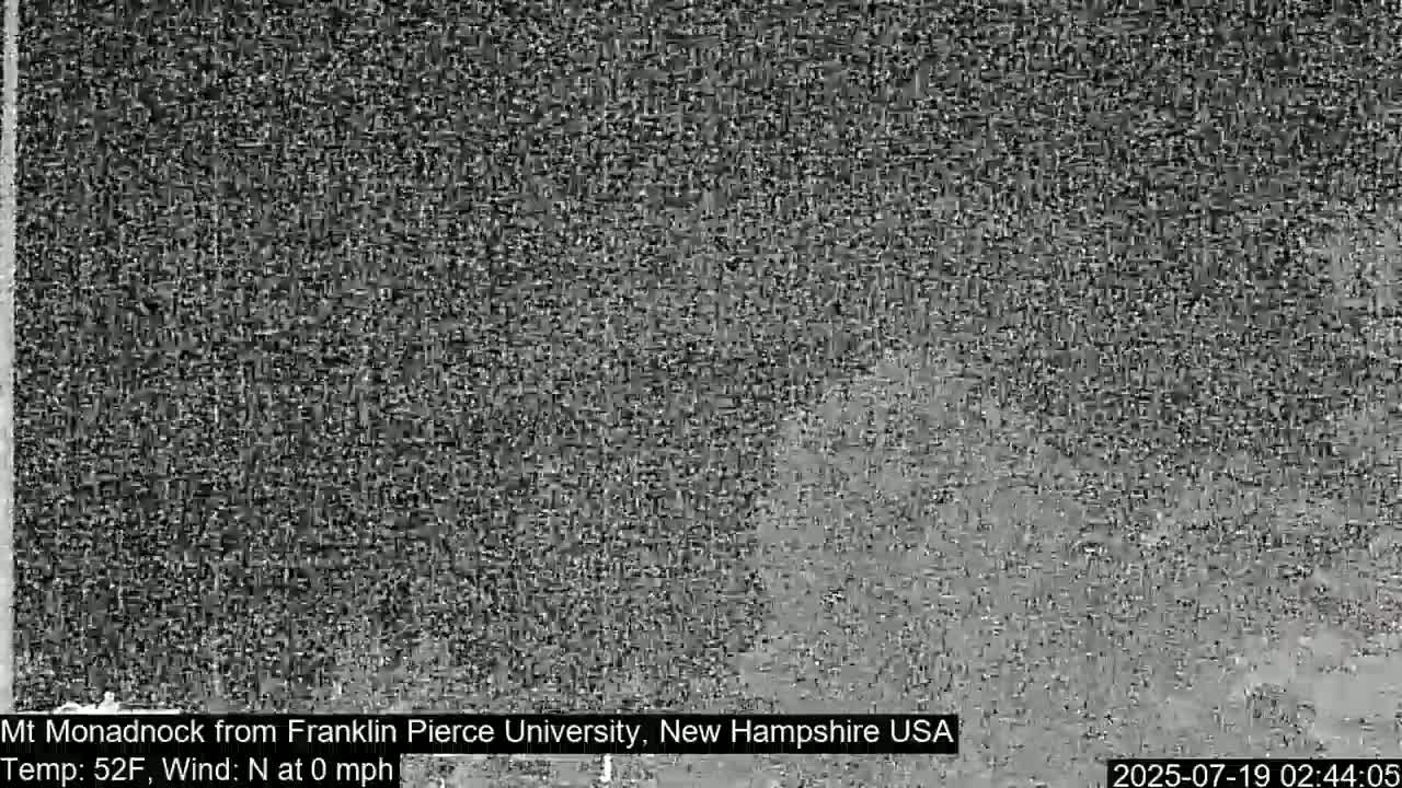 A grainy, monochrome image shows a distant, indistinct view of a landscape in calm conditions.