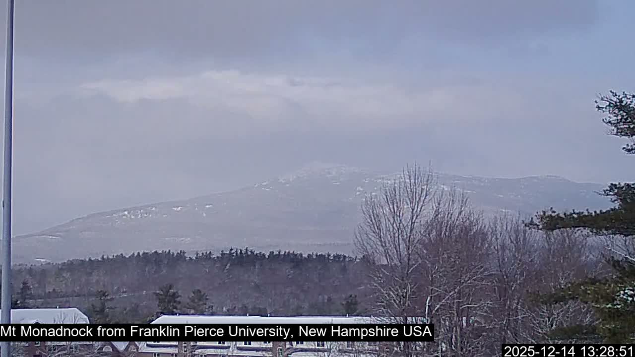 A heavily pixelated and noisy monochrome image captures a very dark outdoor scene at night, featuring faint, indistinct shapes at the bottom and a vertical element on the left, indicating extremely low visibility.