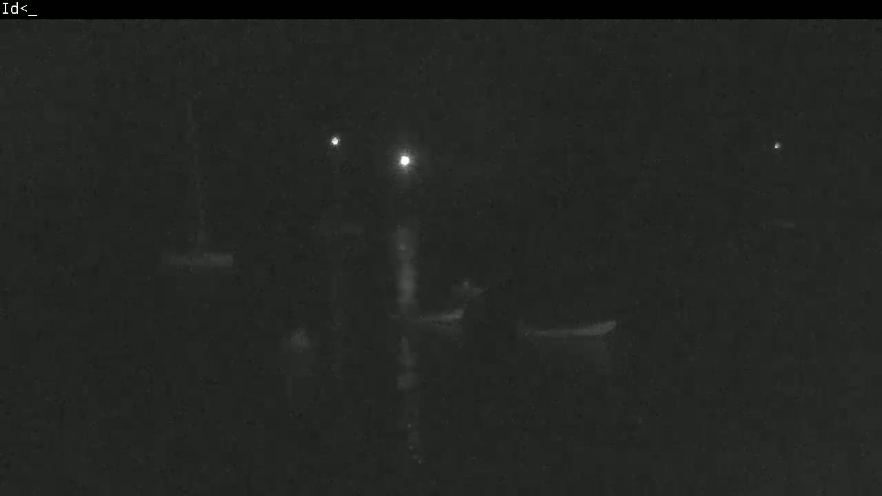A dark, nighttime scene shows several indistinct shapes, possibly boats, illuminated by faint lights.