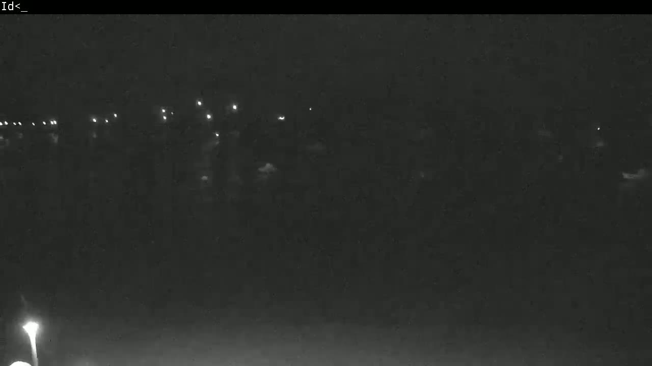 A nighttime, low-light view shows a long line of faint lights in the distance.