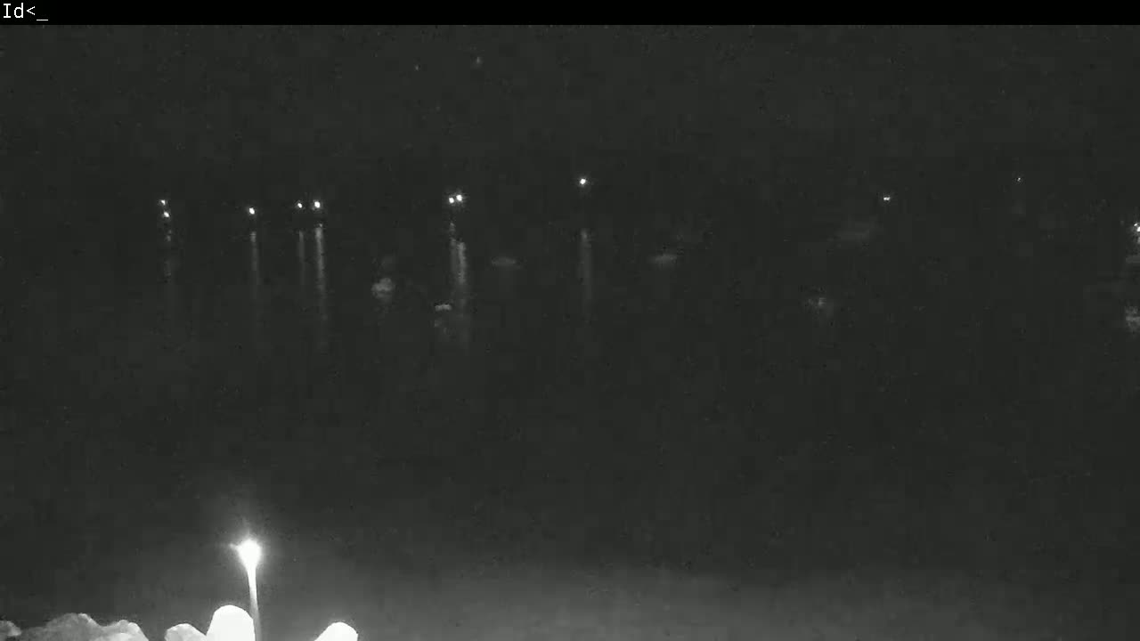 A nighttime view of a dark body of water with several distant lights reflecting on its surface.