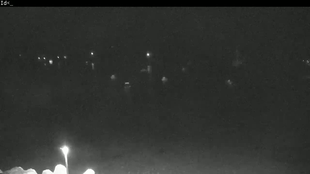 A nighttime, low-light view shows indistinct shapes and a few faint lights possibly indicating vehicles and streetlights.