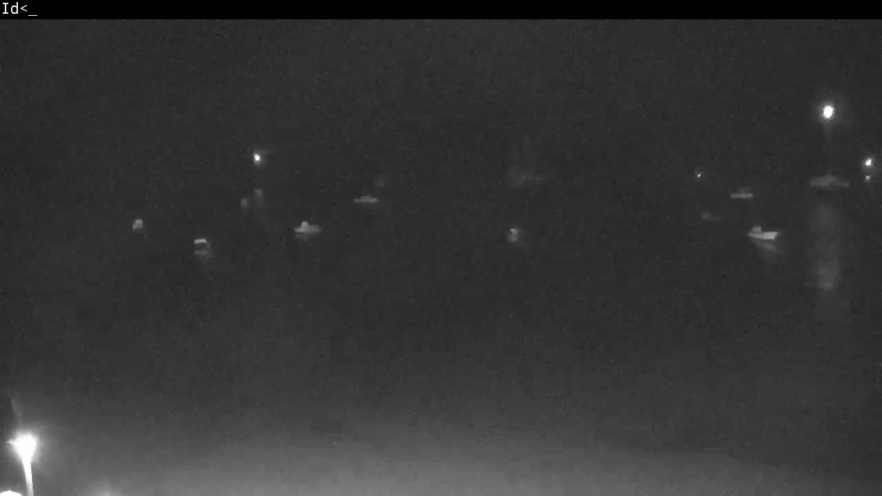 A nighttime, low-light image shows several indistinct objects, possibly vehicles, sparsely scattered across a dark, flat surface.