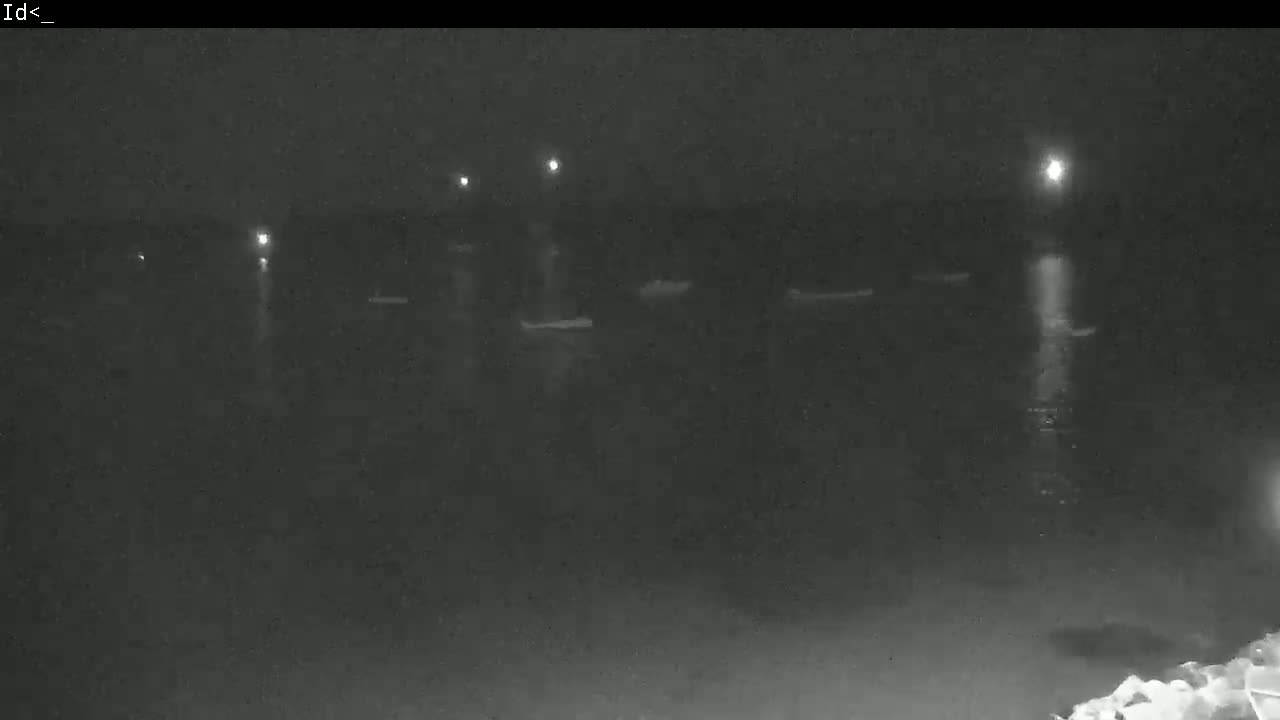 A nighttime, low-light view of a body of water with several indistinct objects and lights in the distance.