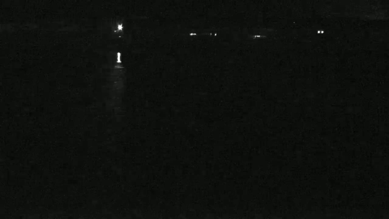 A dark, nighttime scene shows faint lights in the distance across a body of water.