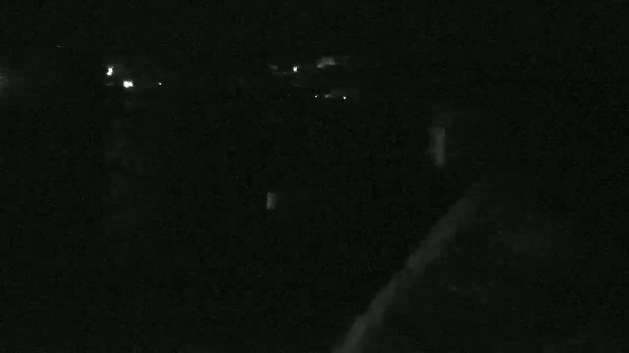 A dark, nighttime scene shows a few distant lights possibly from houses or cars.