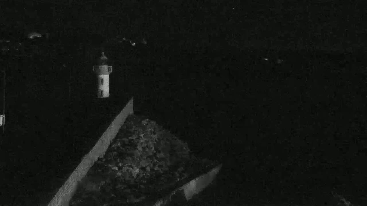 A lighthouse stands on a dark, rocky coast at night.