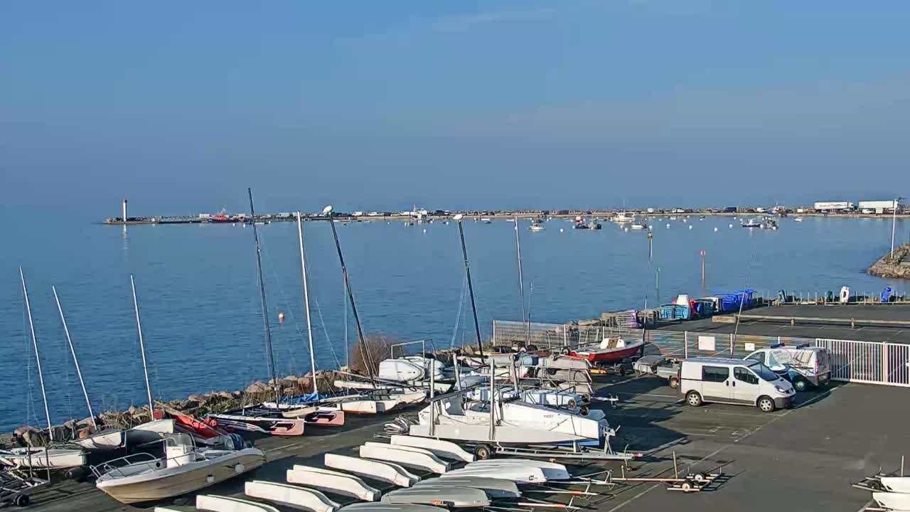 A harbor filled with sailboats and motorboats under a clear blue sky.