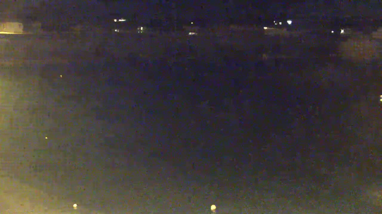 A dark, nighttime outdoor scene shows a flat, empty expanse of land with a few distant lights.
