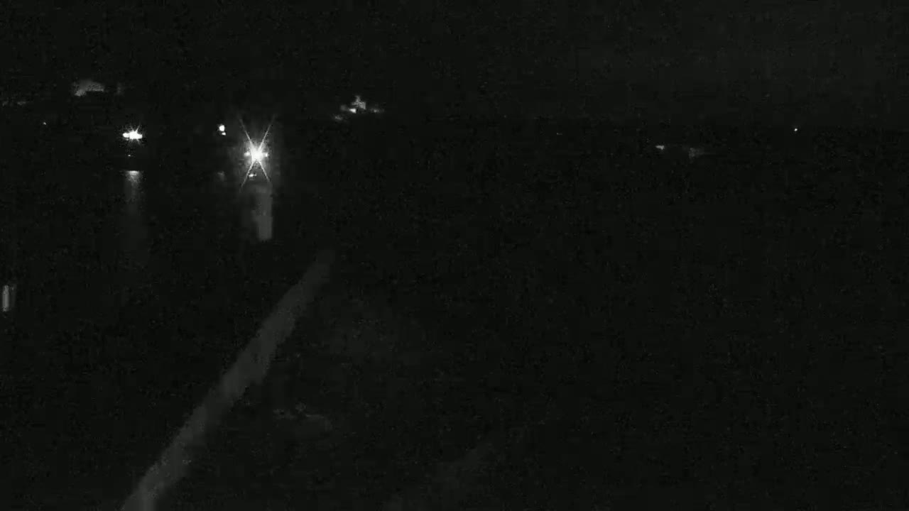 A nighttime, low-light view shows a dark road or path with faint lights in the distance.