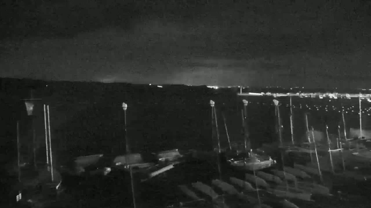 A nighttime, low-light view of a marina filled with boats under a dark, cloudy sky.