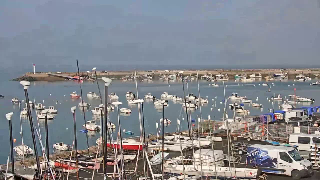 Numerous small boats are moored in a calm harbor on a hazy day.