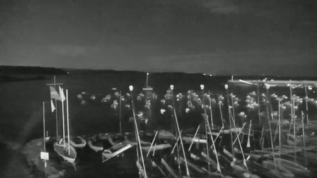 A nighttime, low-light view of numerous small boats moored in a harbor, under a dark sky.