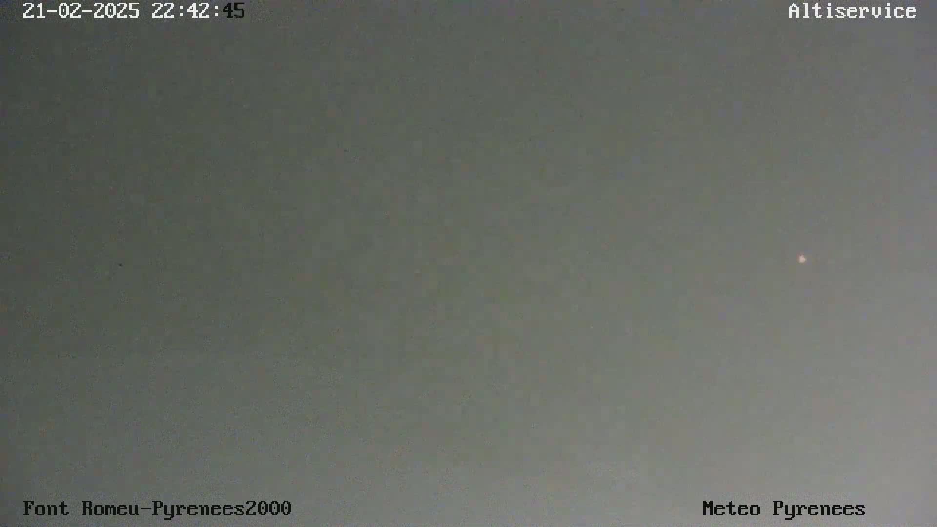 A single, faint light is visible in a muted gray, overcast sky.