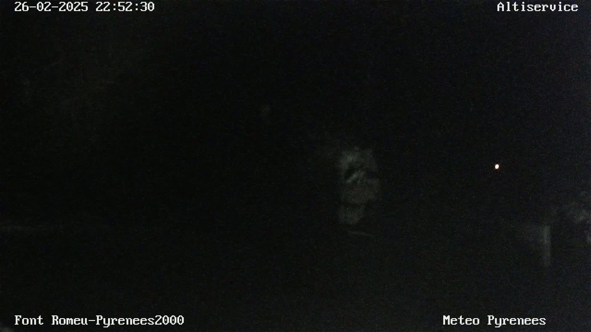 A nighttime, low-light image shows a dark, mostly featureless scene with a single, faint light visible in the distance.