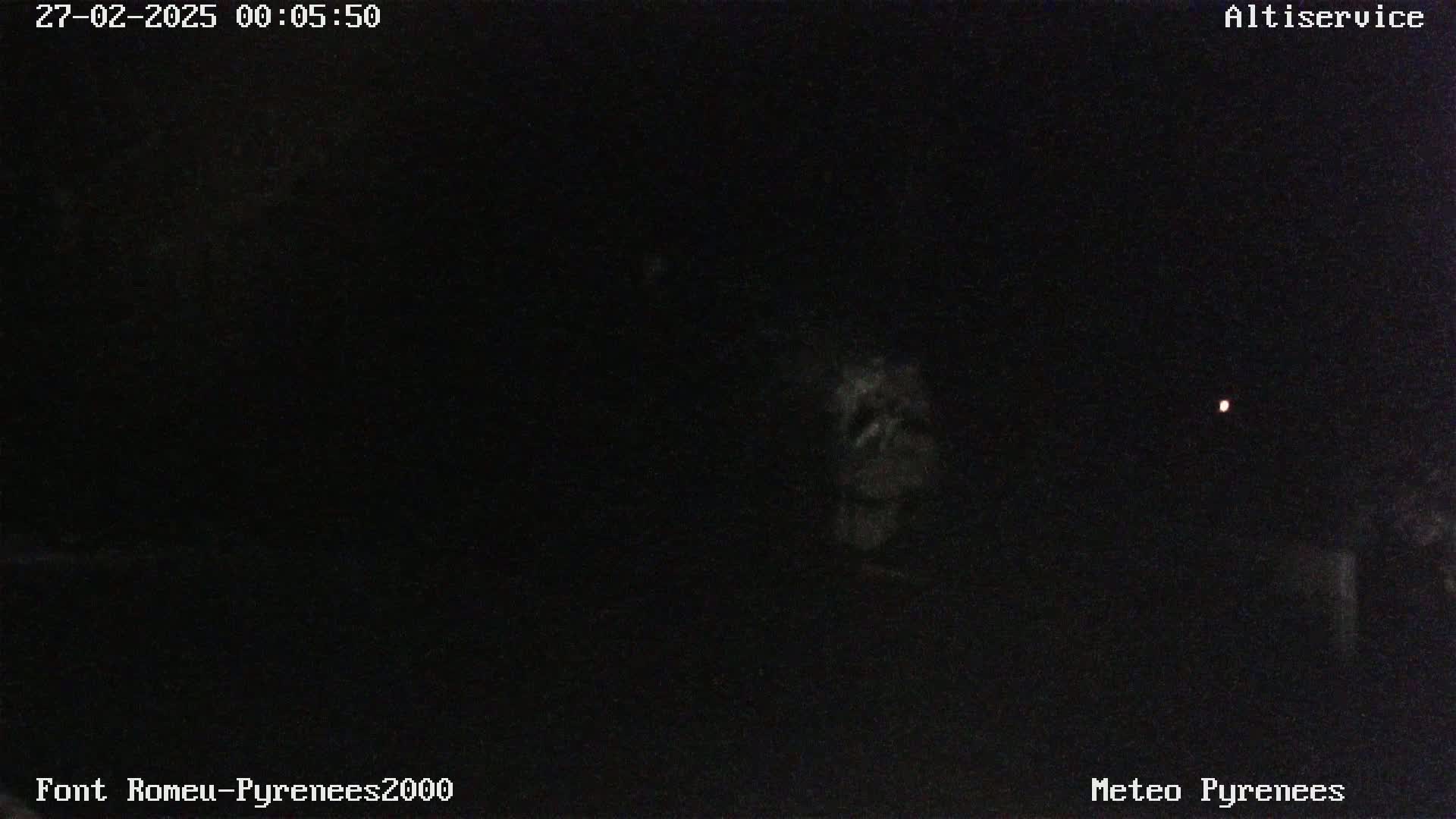 A nighttime, low-light image shows a dark, mostly featureless scene with a single, faint light visible in the distance.