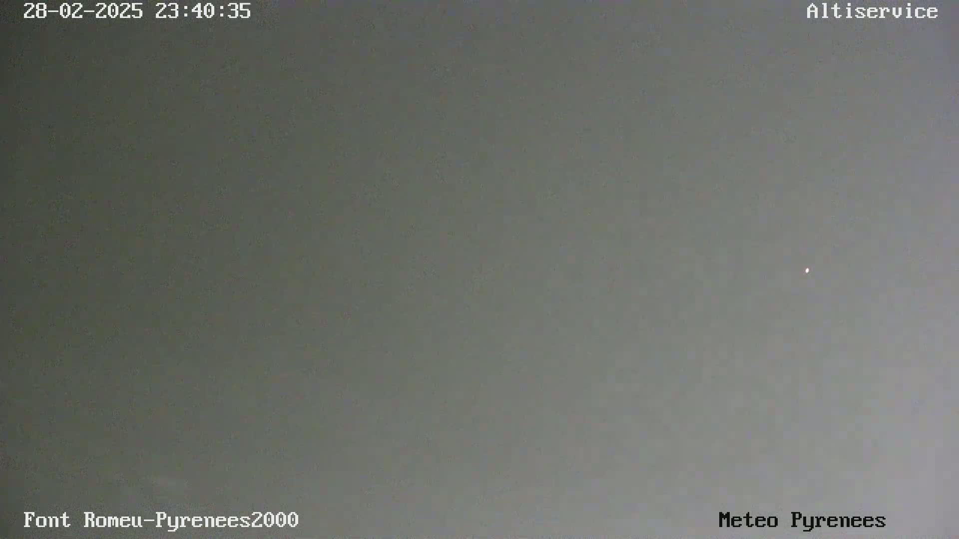 A single, faint light is visible in a grey, overcast sky.