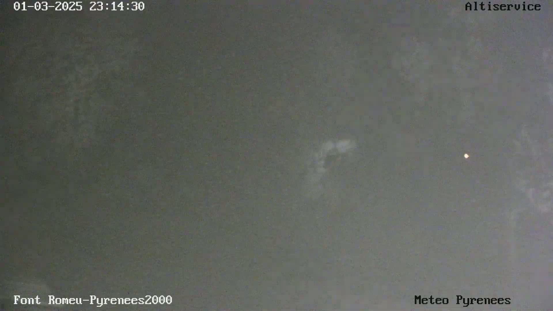 A dark, overcast night sky shows a faint, blurry light source and a small, bright light in the distance.