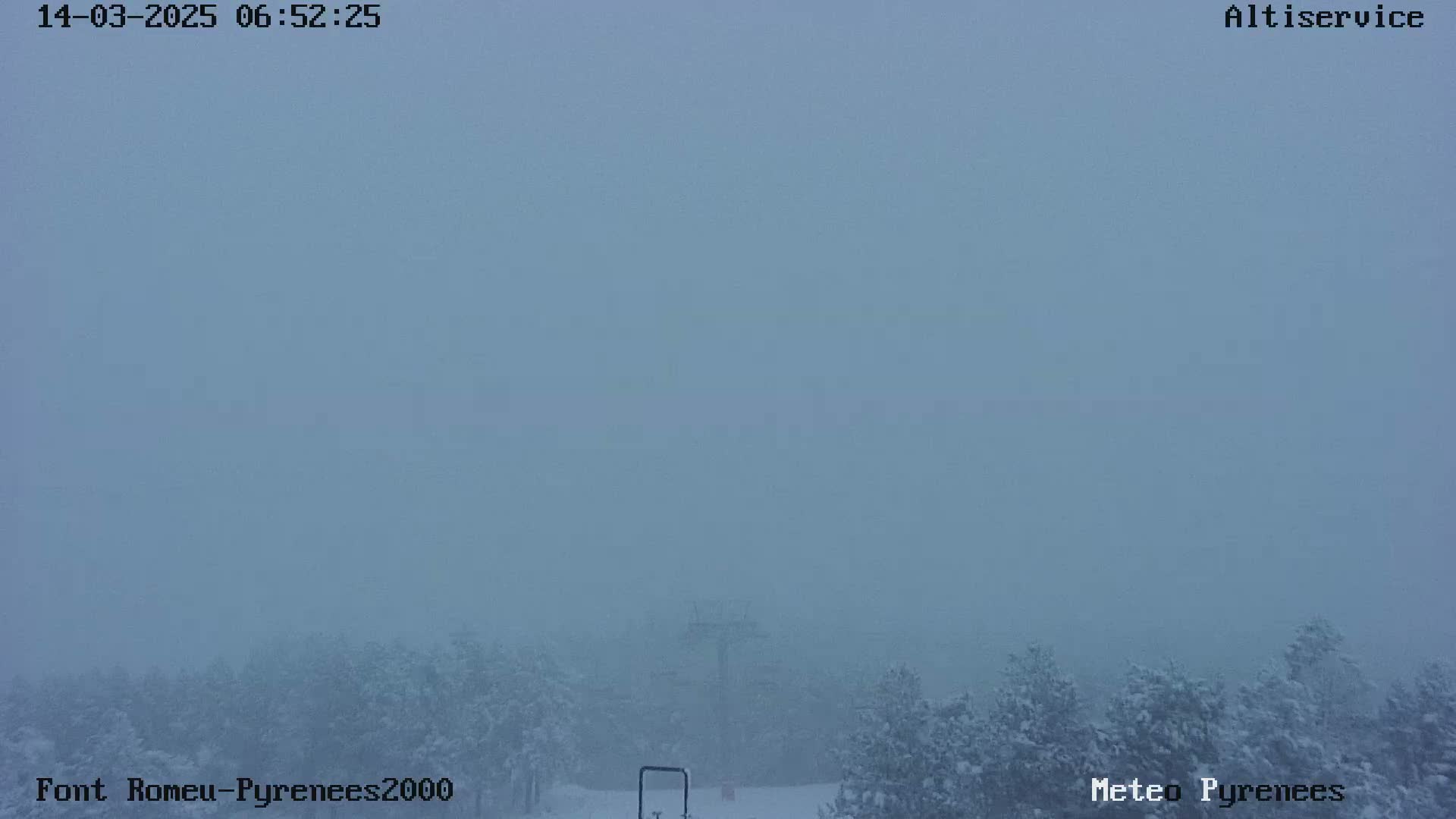 A snowy, foggy scene shows a sparsely wooded area with a tall structure in the center distance.