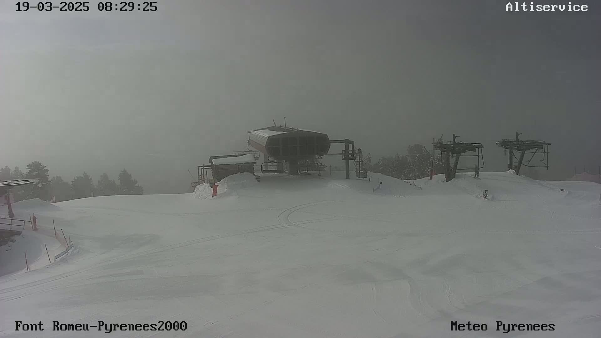 A snow-covered ski slope with a chairlift and two ski lifts is visible in foggy conditions.