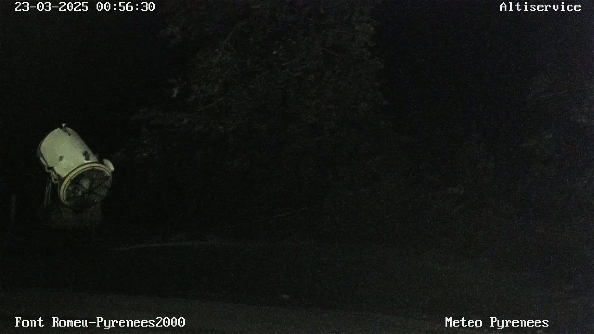A light-colored cylindrical object with a fan-like structure is visible at night in a dark, outdoor setting.