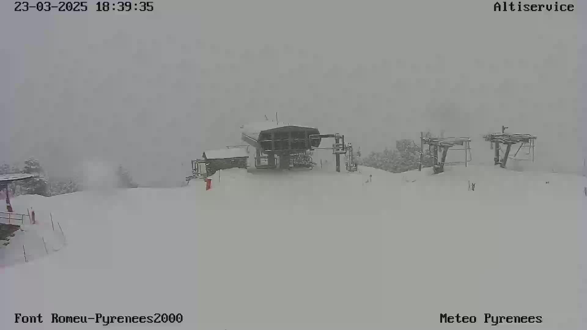 A snow-covered ski lift station is barely visible in heavy snowfall.