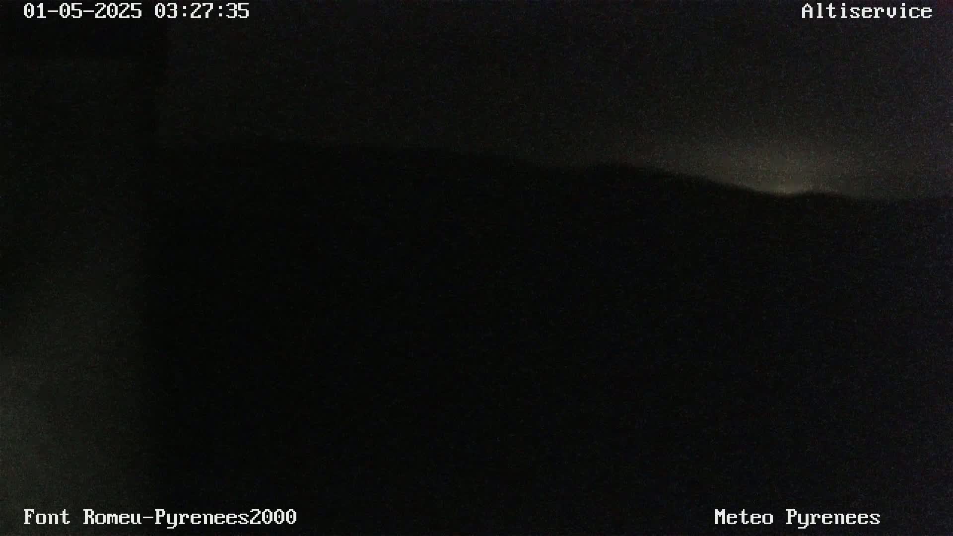 A dark, nighttime landscape is visible, showing a dimly lit mountain range under a mostly clear sky.