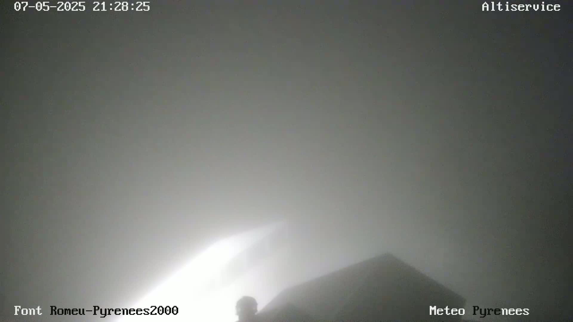 A foggy, nighttime scene shows a dark building and a silhouetted figure.