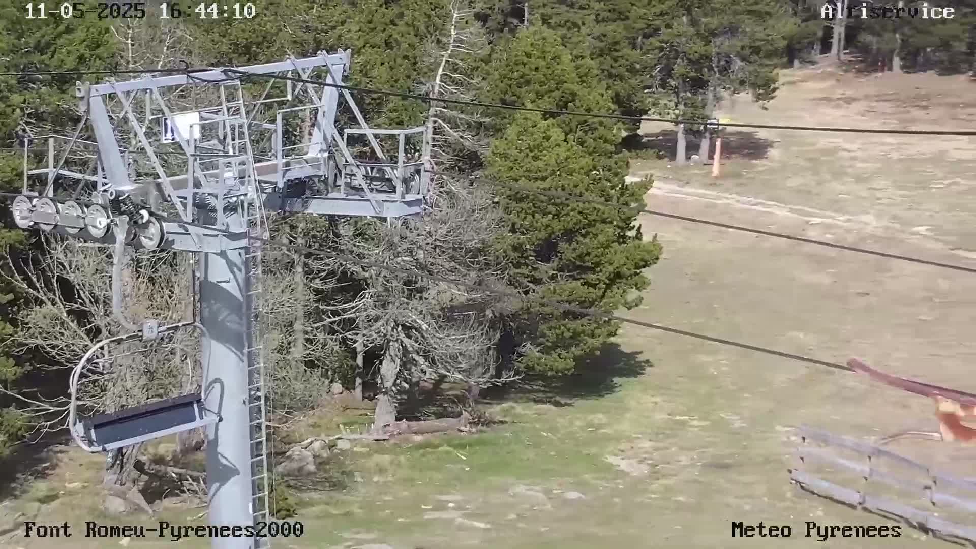 A chairlift sits amidst a sunny, sparsely wooded landscape.