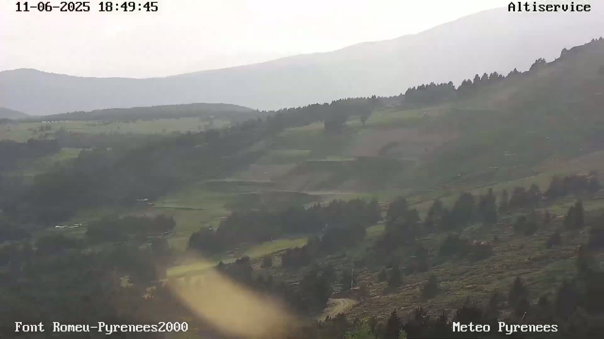 A hazy, overcast view of a vast, rolling landscape with sparse vegetation and distant mountains.