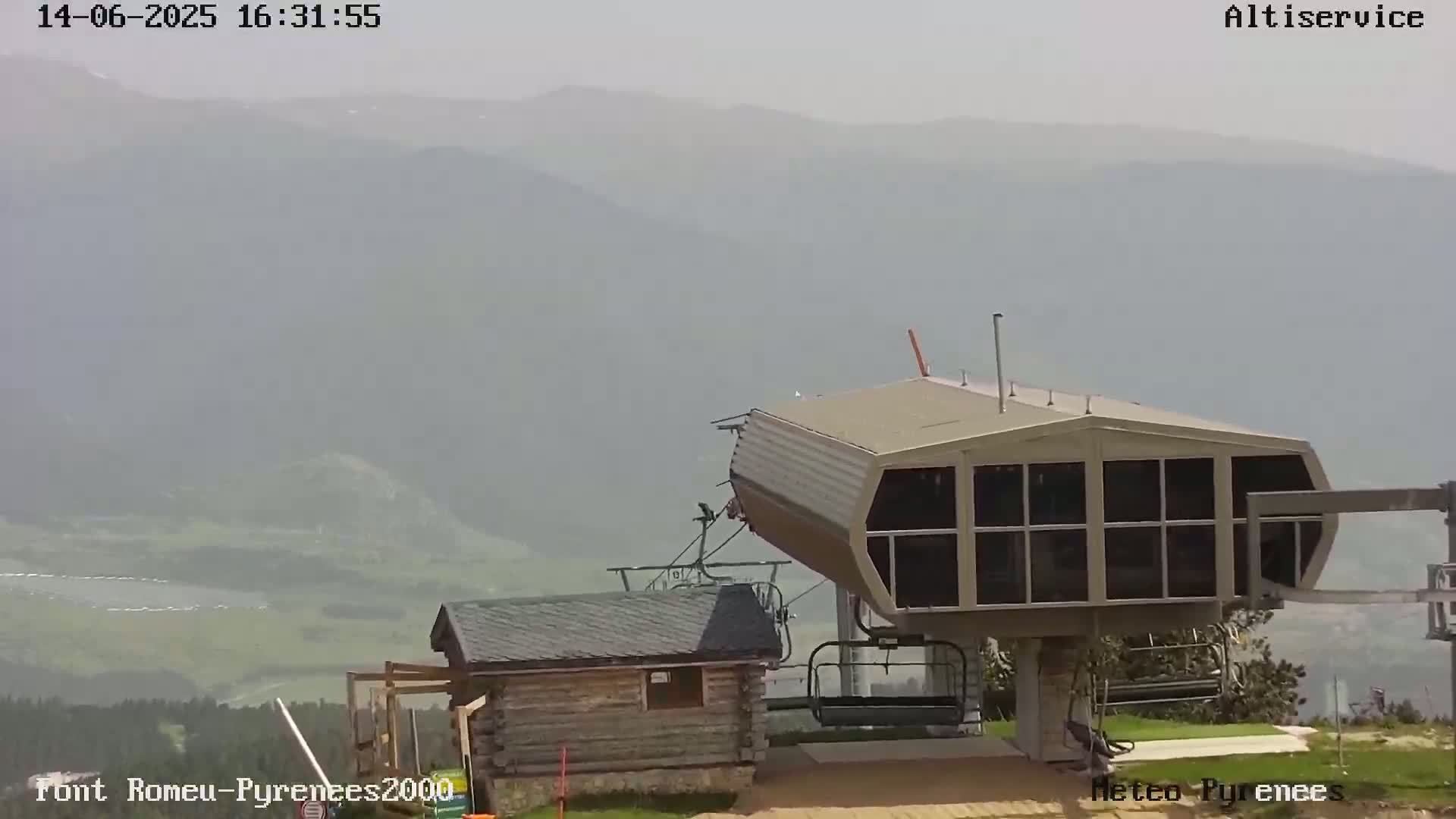 A hazy mountain vista is visible behind a chairlift station and small wooden building.