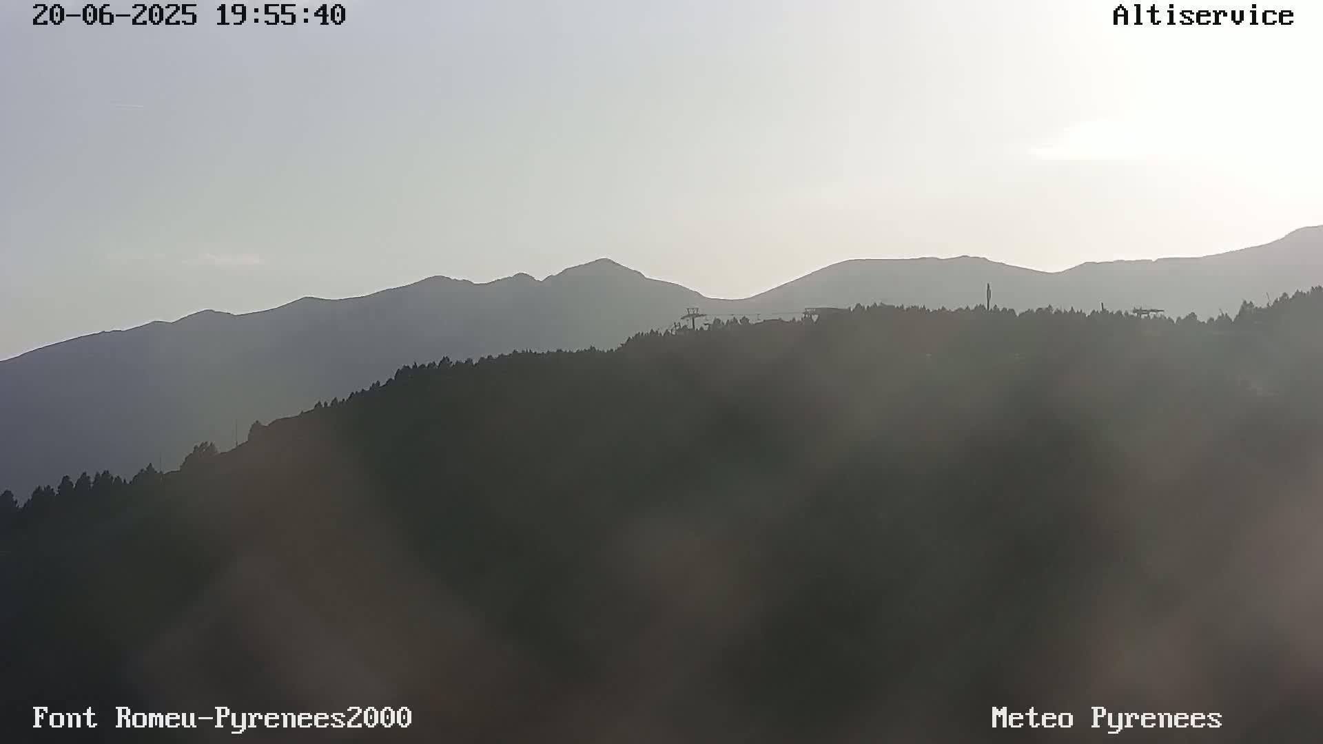 A hazy, dusky view shows a mountain range silhouetted against a pale sky.