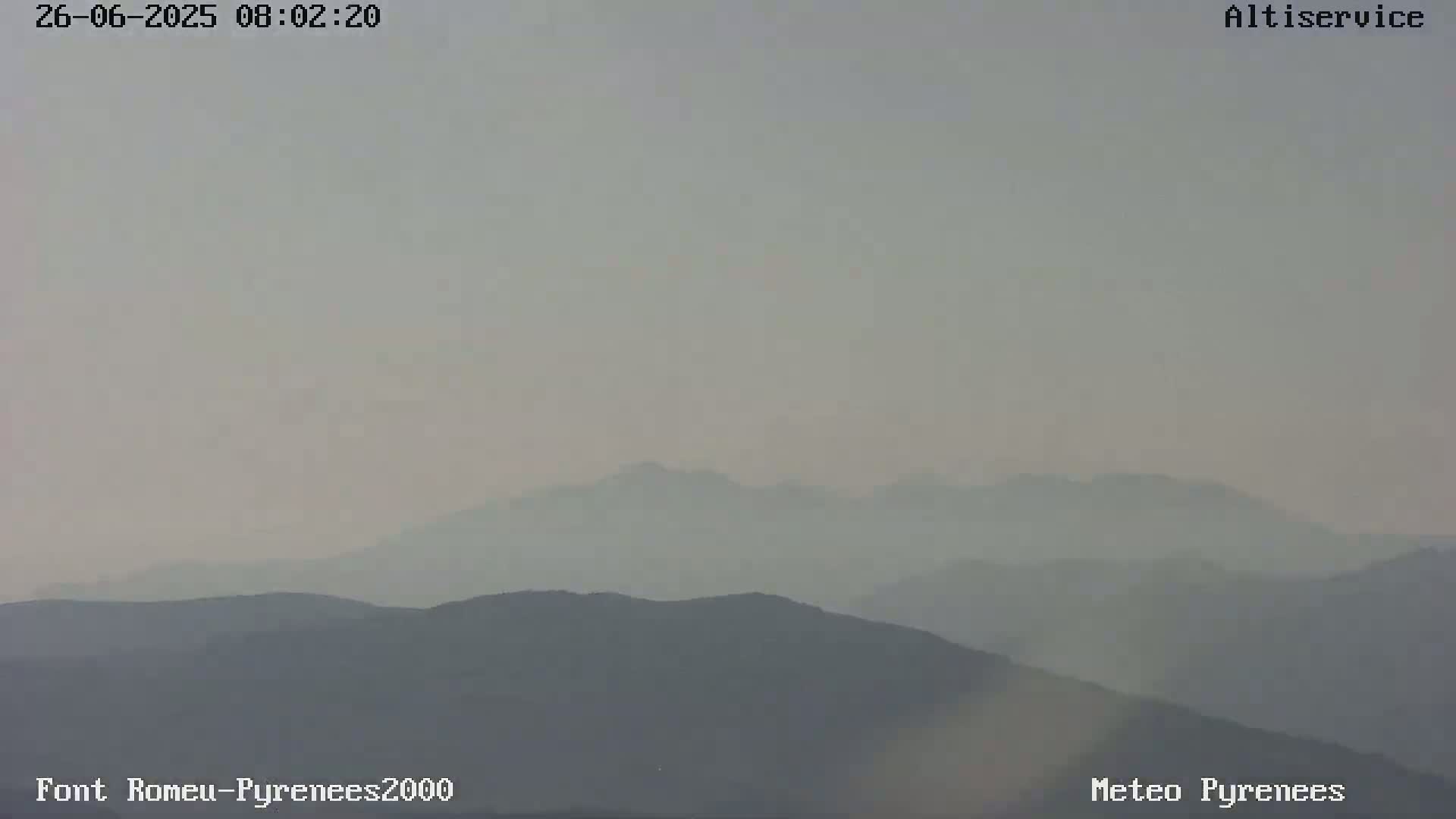 A hazy, muted view of rolling mountains under a pale sky.