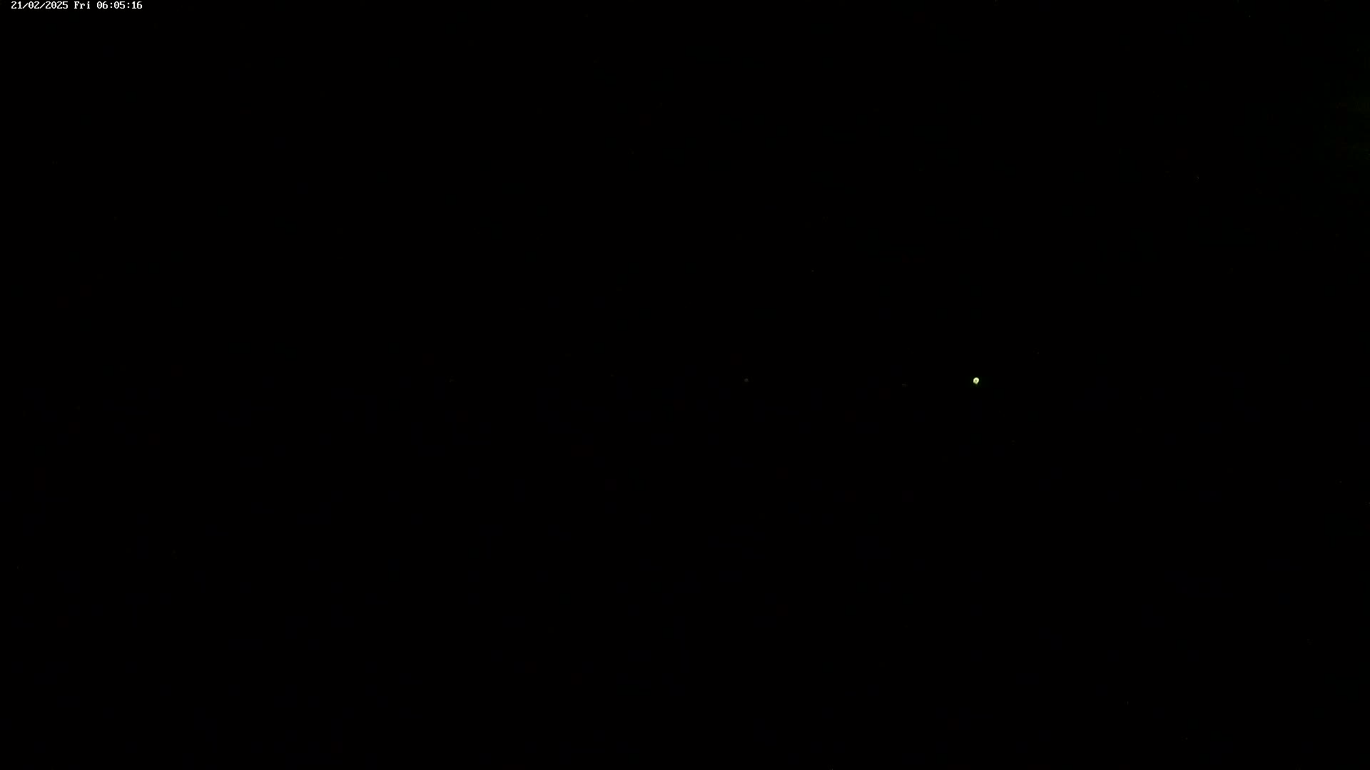 A single, small, faint light is visible in an otherwise completely dark nighttime scene.