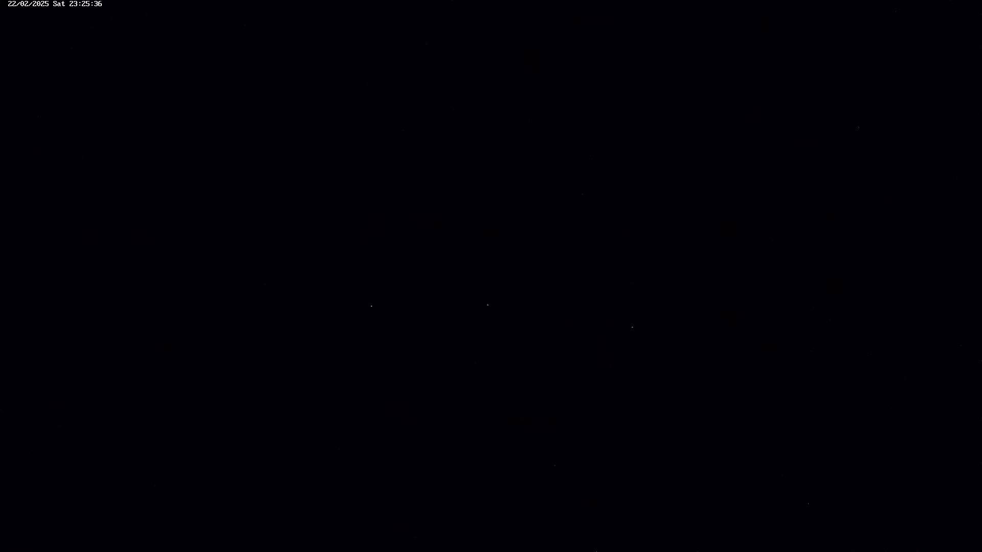 A mostly dark image shows a few faint lights against a black background.