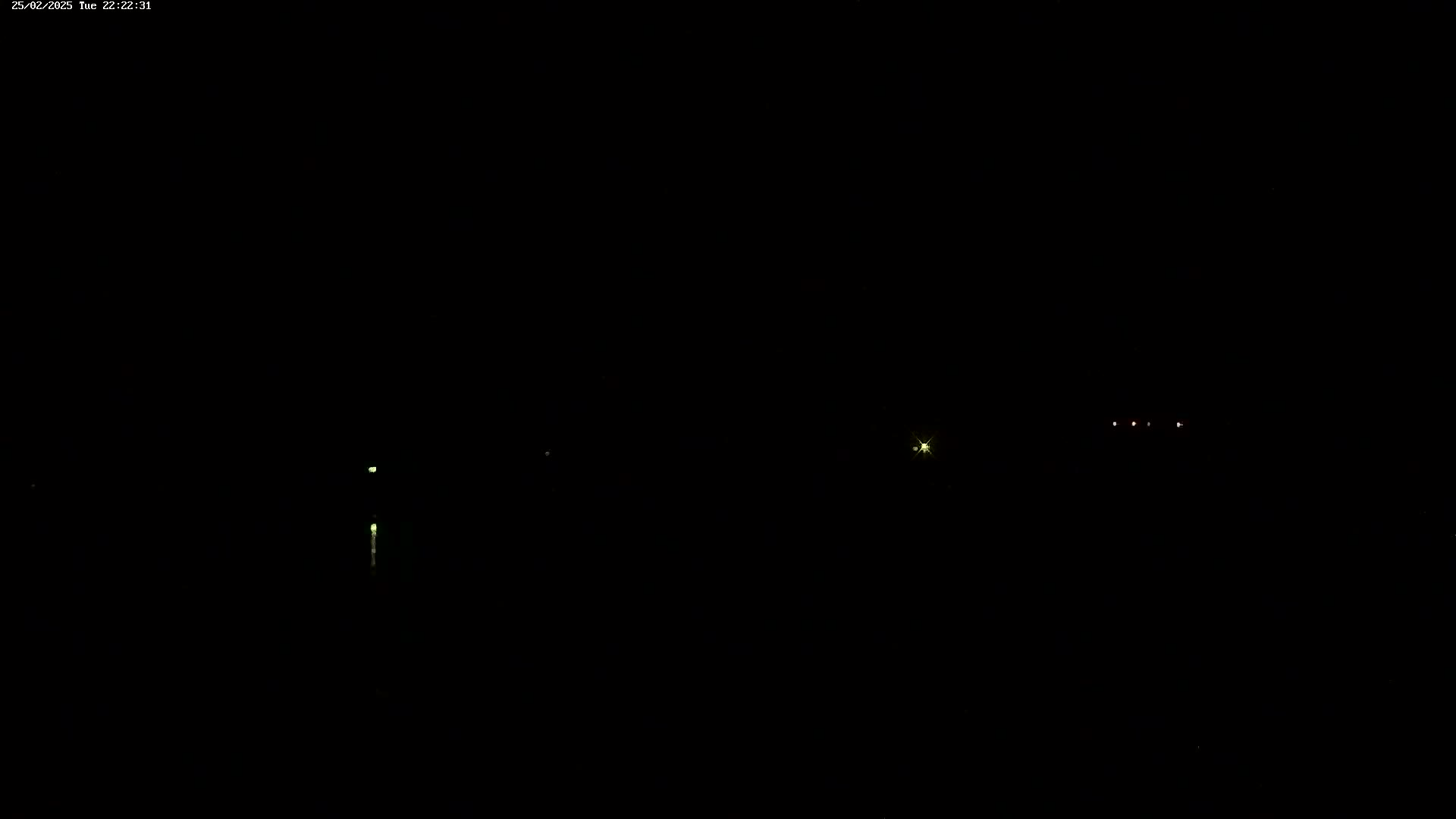 A dark nighttime scene shows several faint lights in the distance.