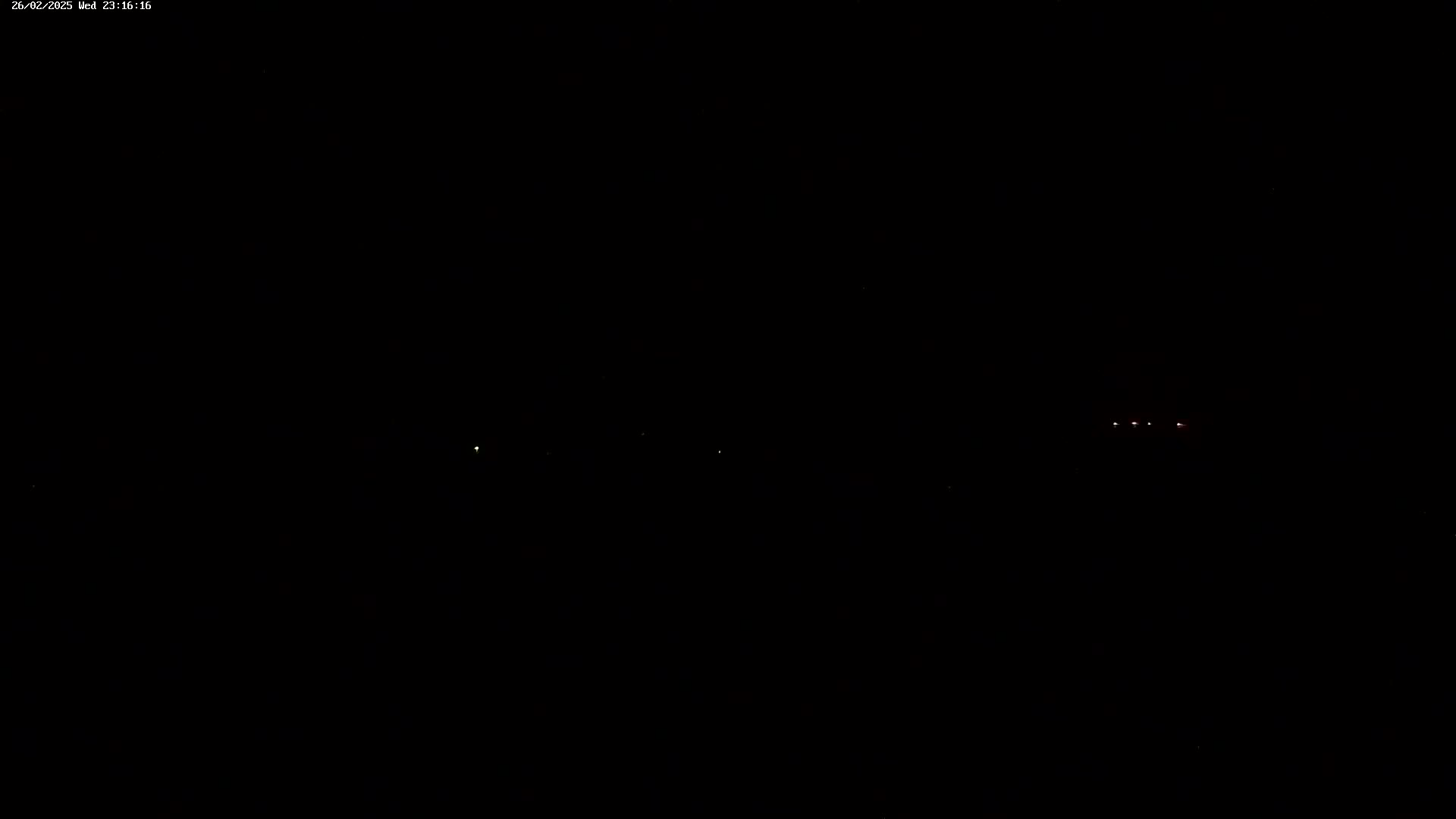 A nighttime scene shows a few faint lights in the distance under a dark sky.