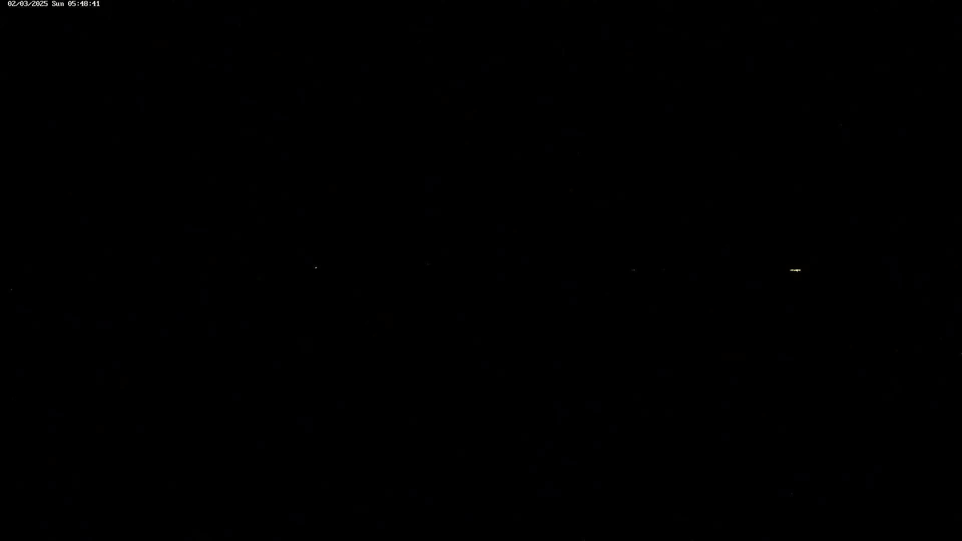 A nighttime scene shows several faint lights in the distance on a dark horizon.
