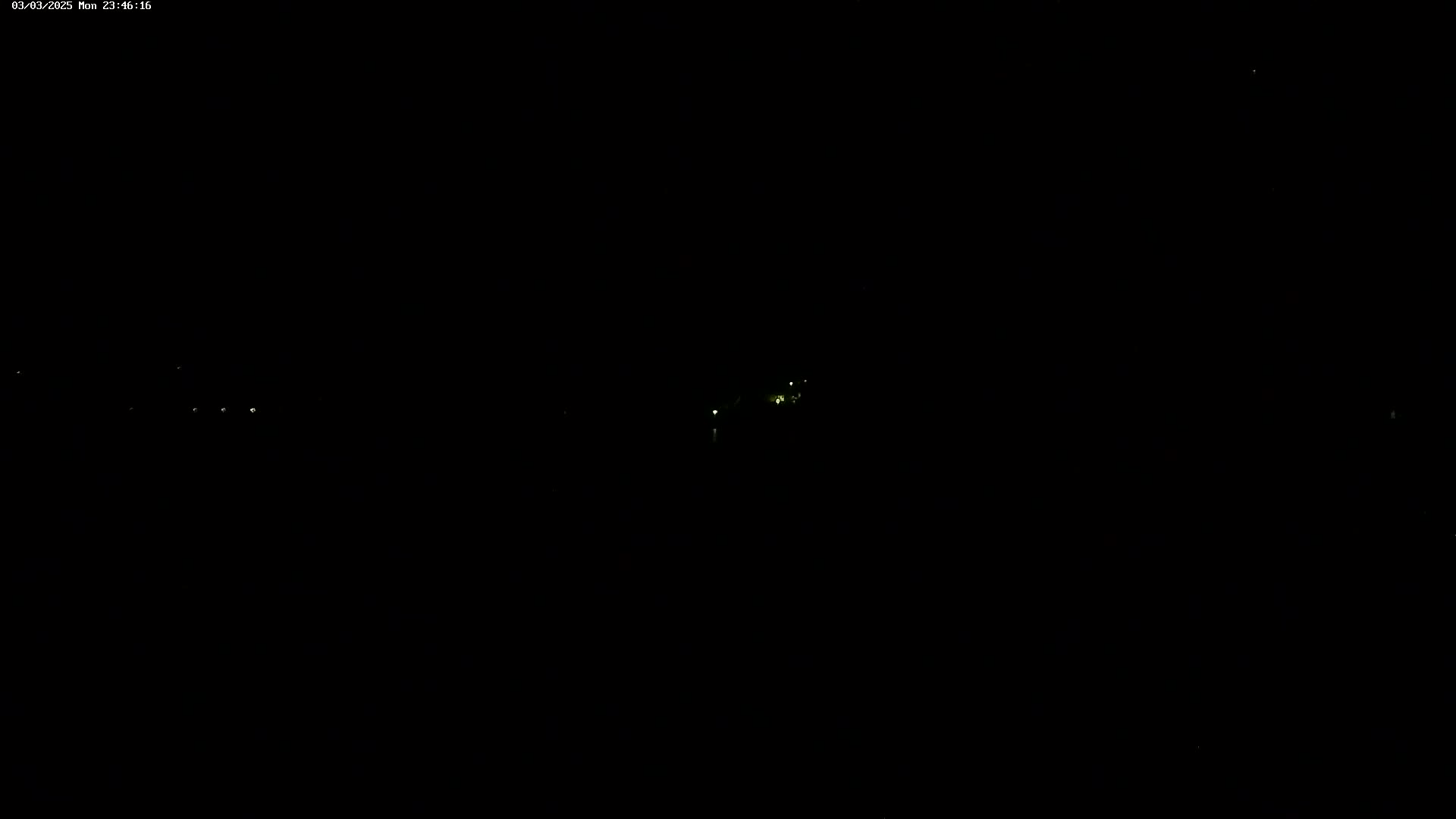 A nighttime, long-range view shows several faint lights in the distance.