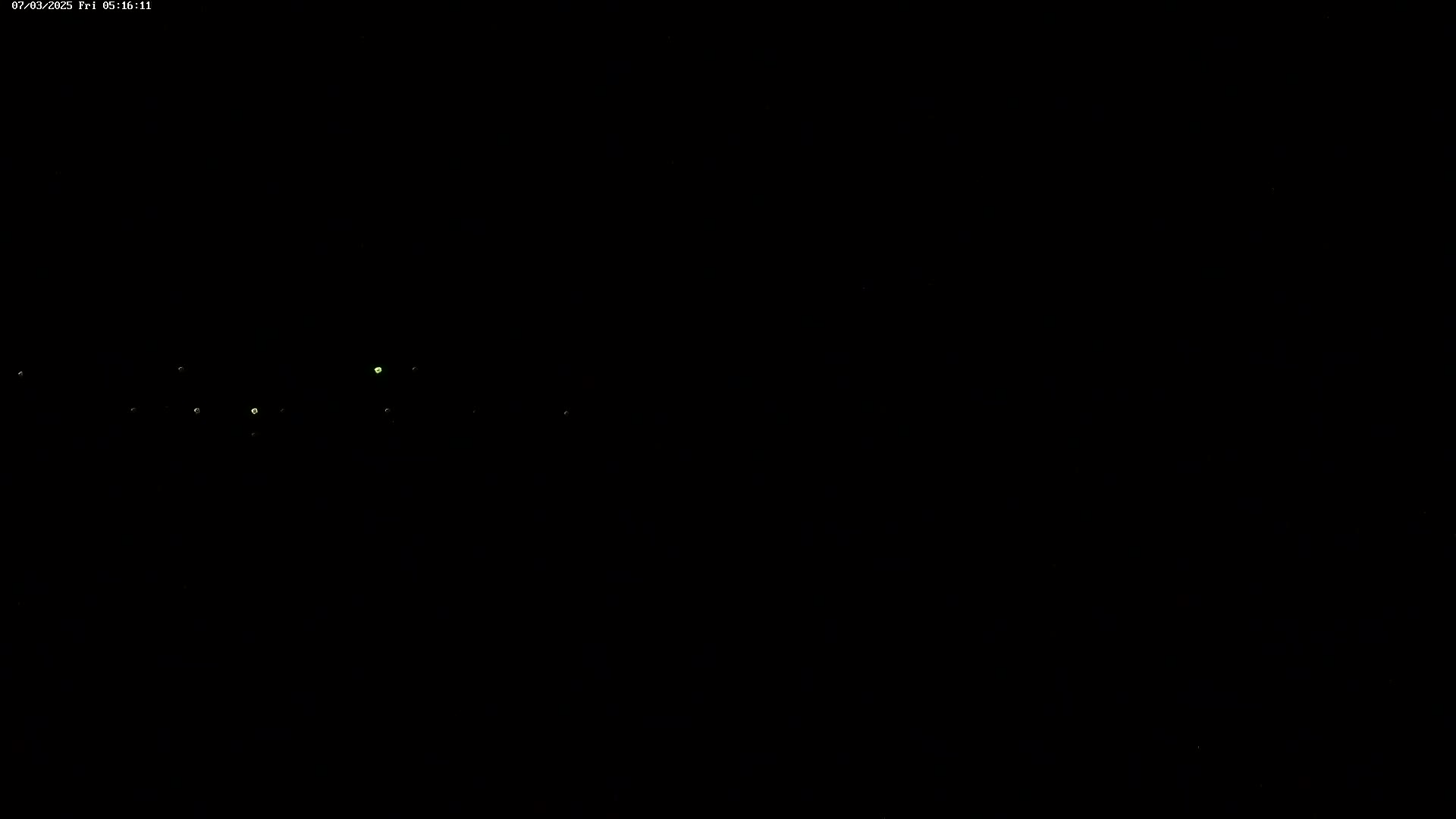 A dark, nighttime scene shows several faint, distant lights in the upper portion of the frame.