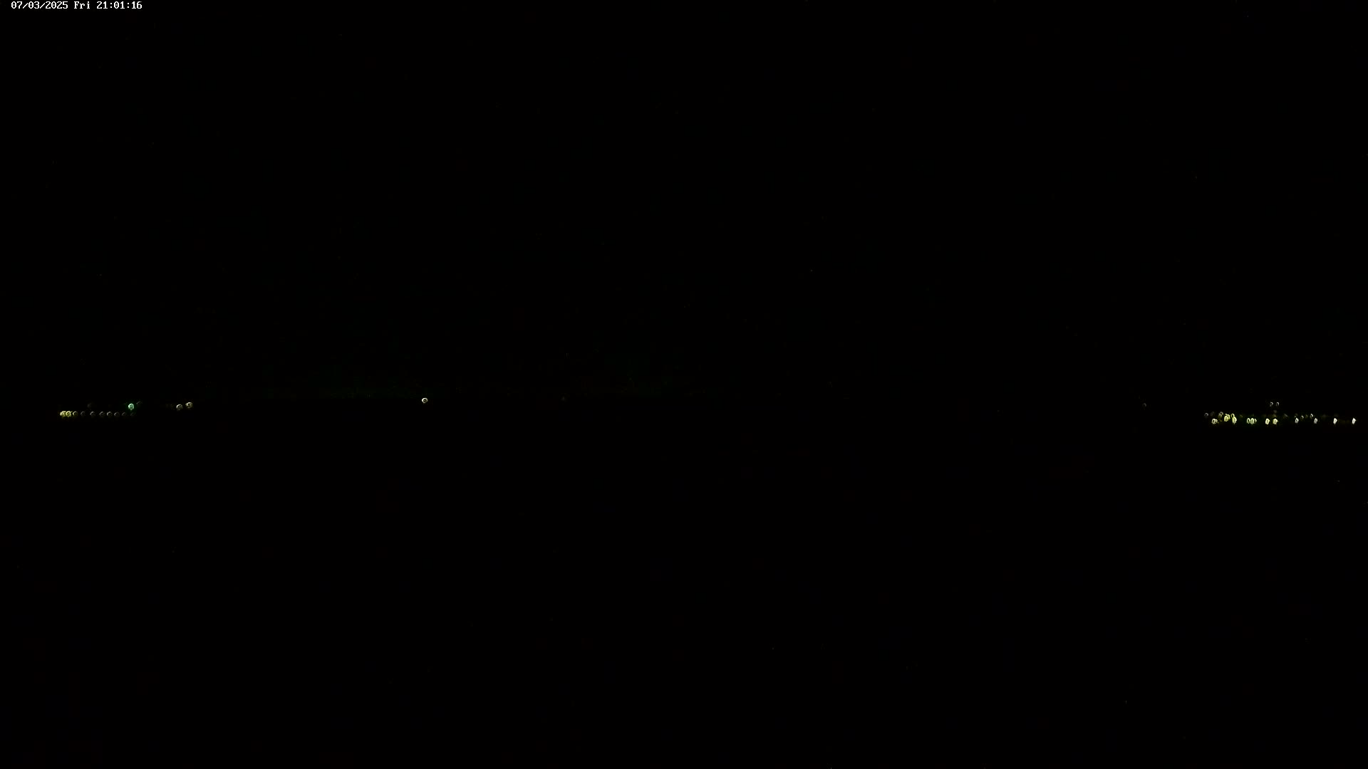 Faint lights are visible on the horizon at night.