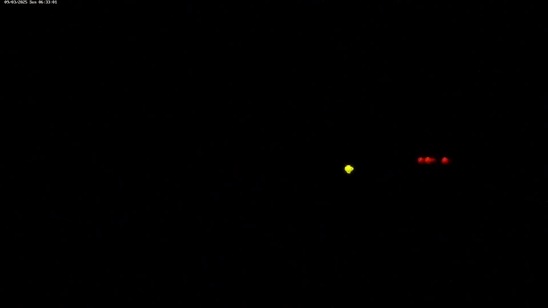 A single yellow light and two red lights are visible in the darkness.