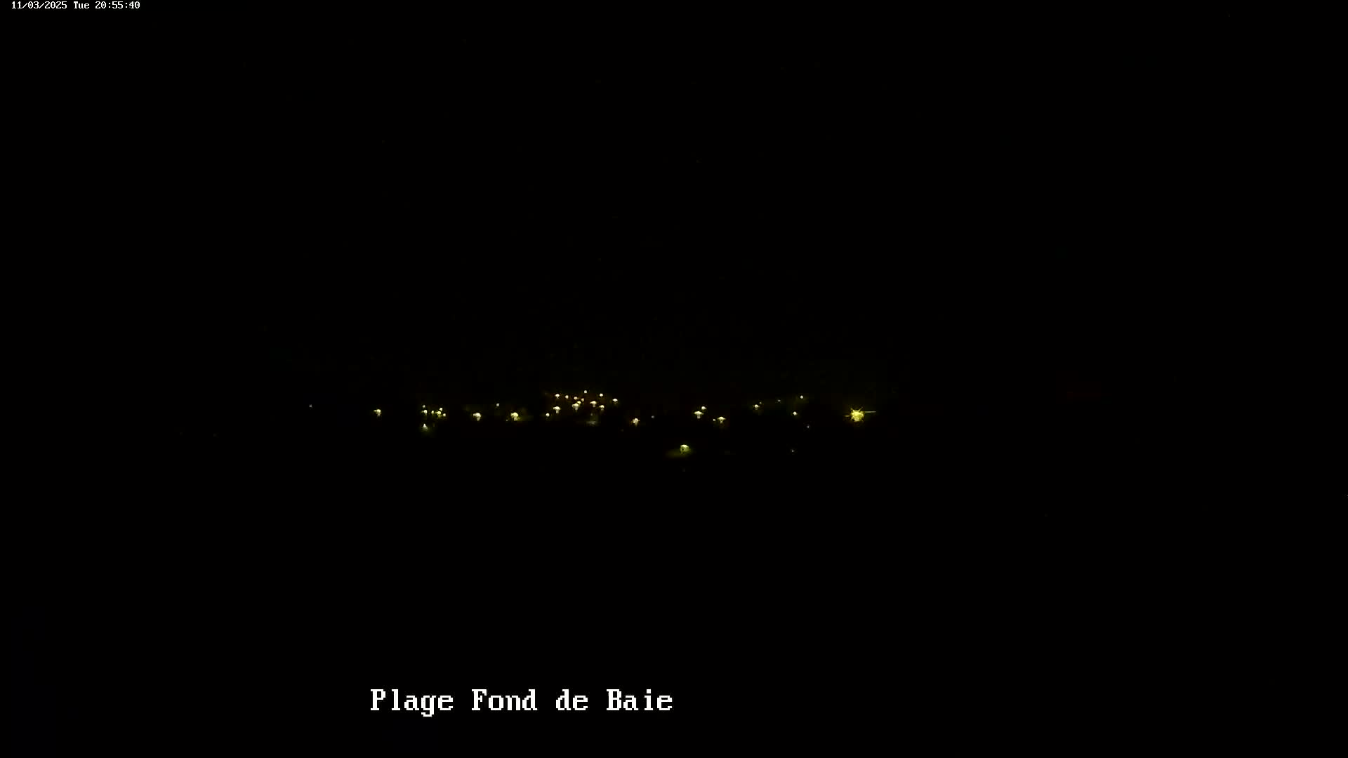 A dark nighttime scene shows a scattering of faint, yellow lights in the distance.