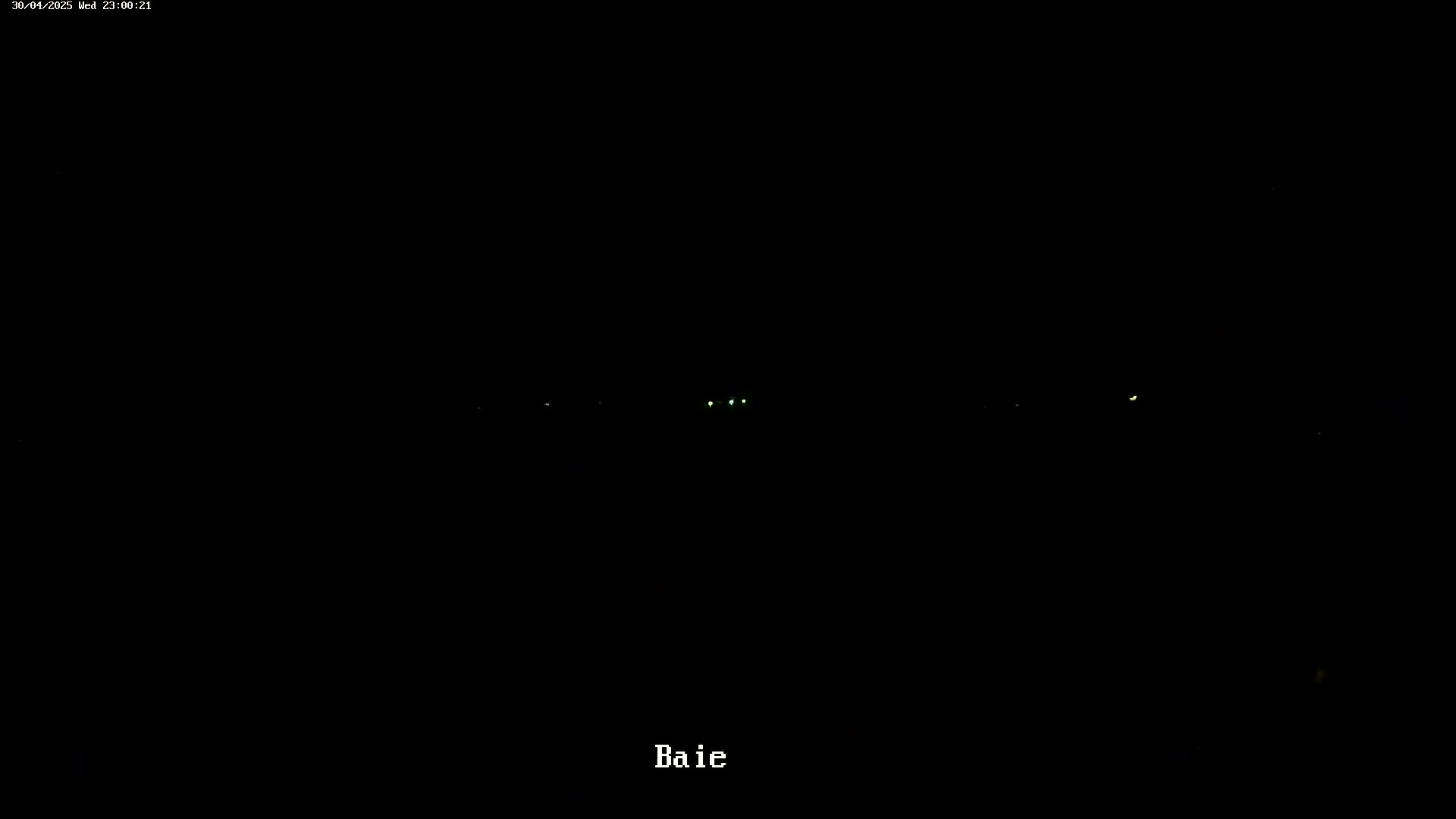 A nighttime, dark scene shows several faint, distant lights in the darkness.