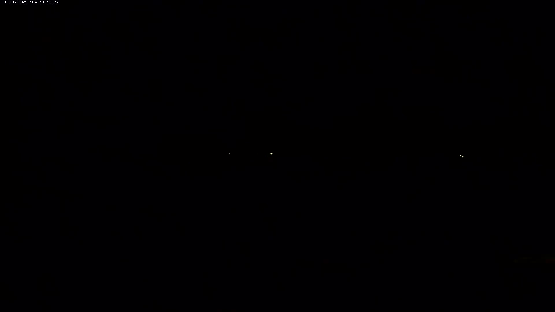 Three faint lights are visible in the distance against a completely dark, nighttime sky.