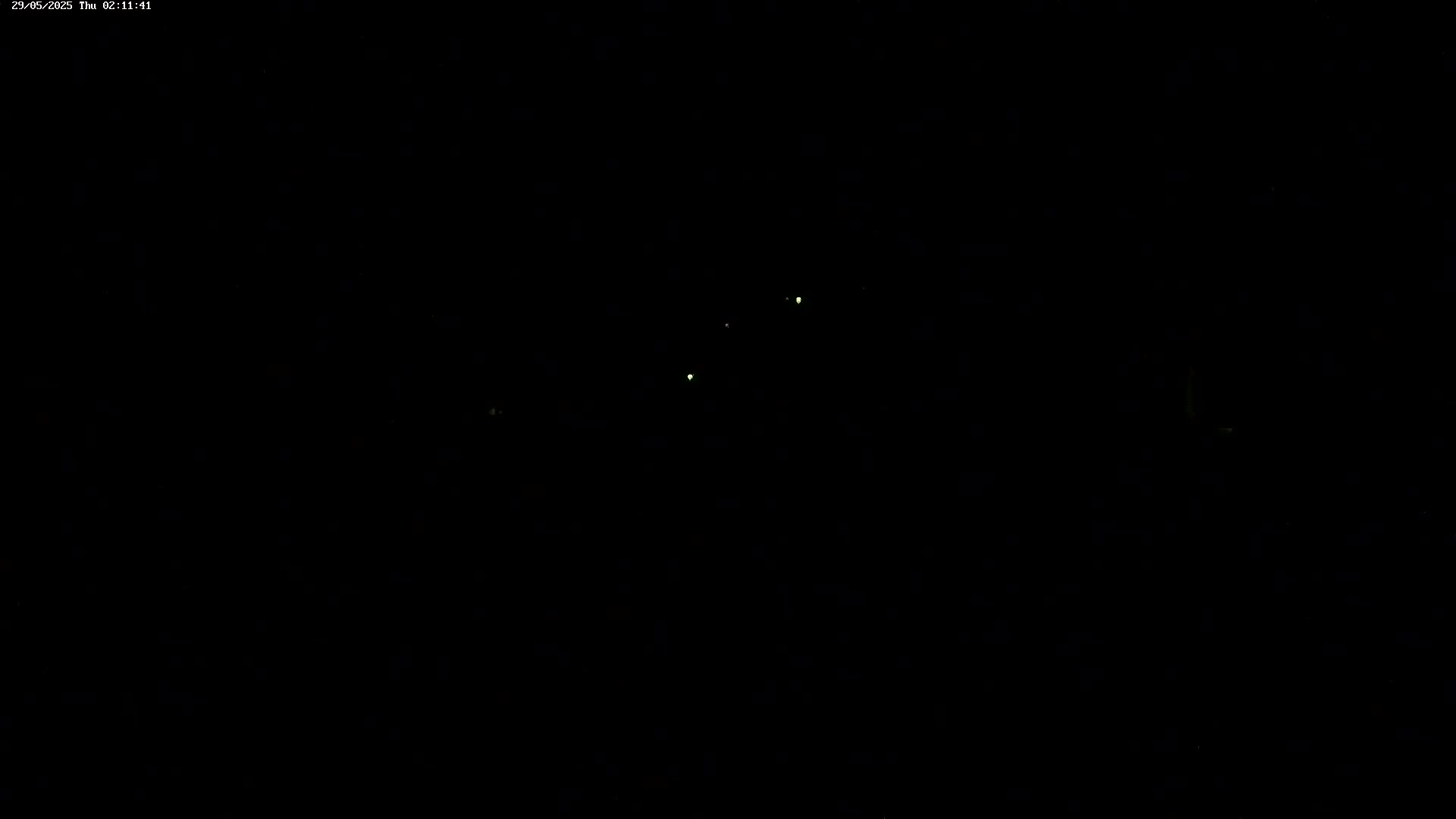 A dark nighttime scene shows a few faint, distant lights.