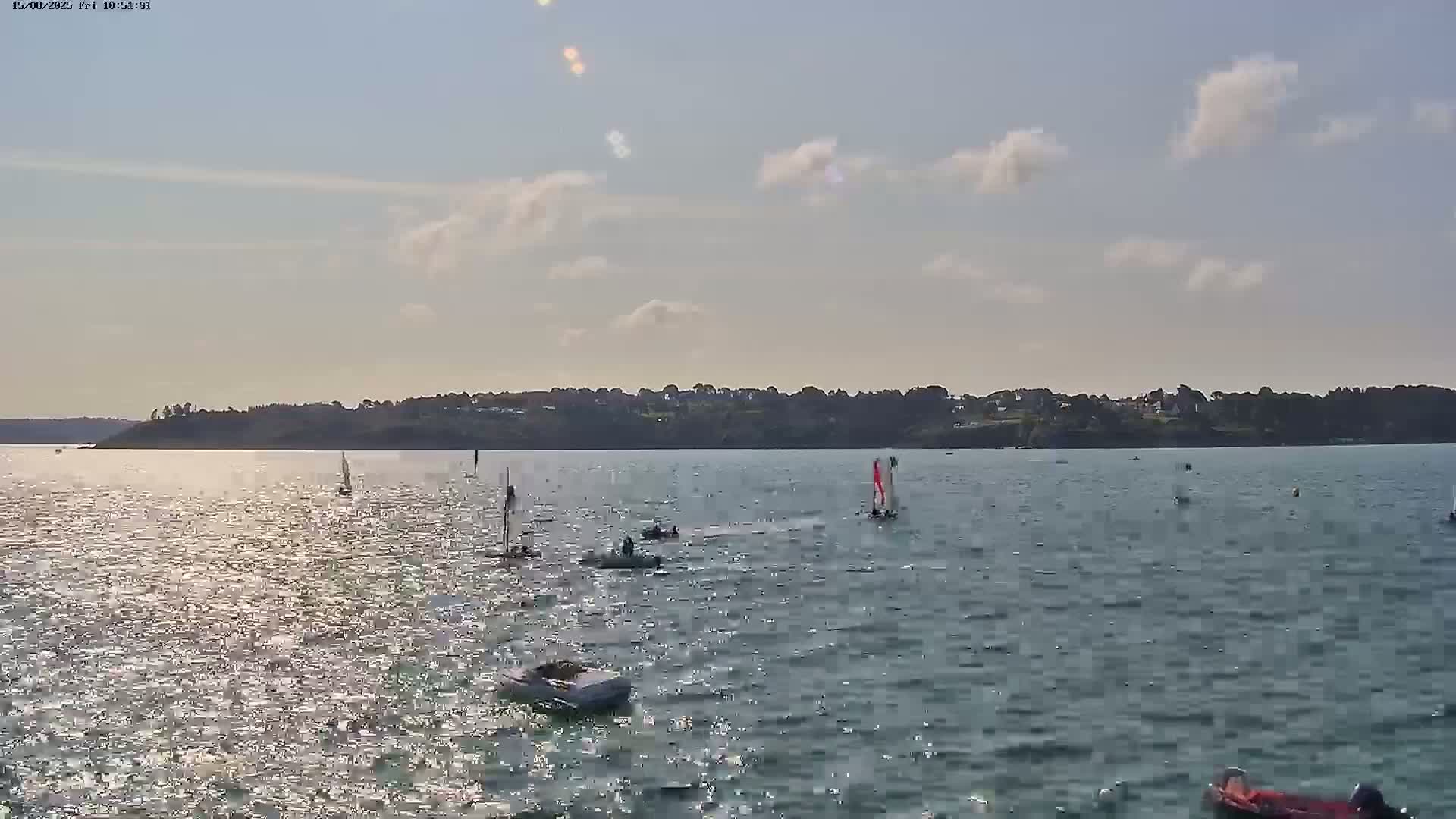 A calm, overcast day at a coastal town, with small waves lapping the shore and two small boats moored in the water.