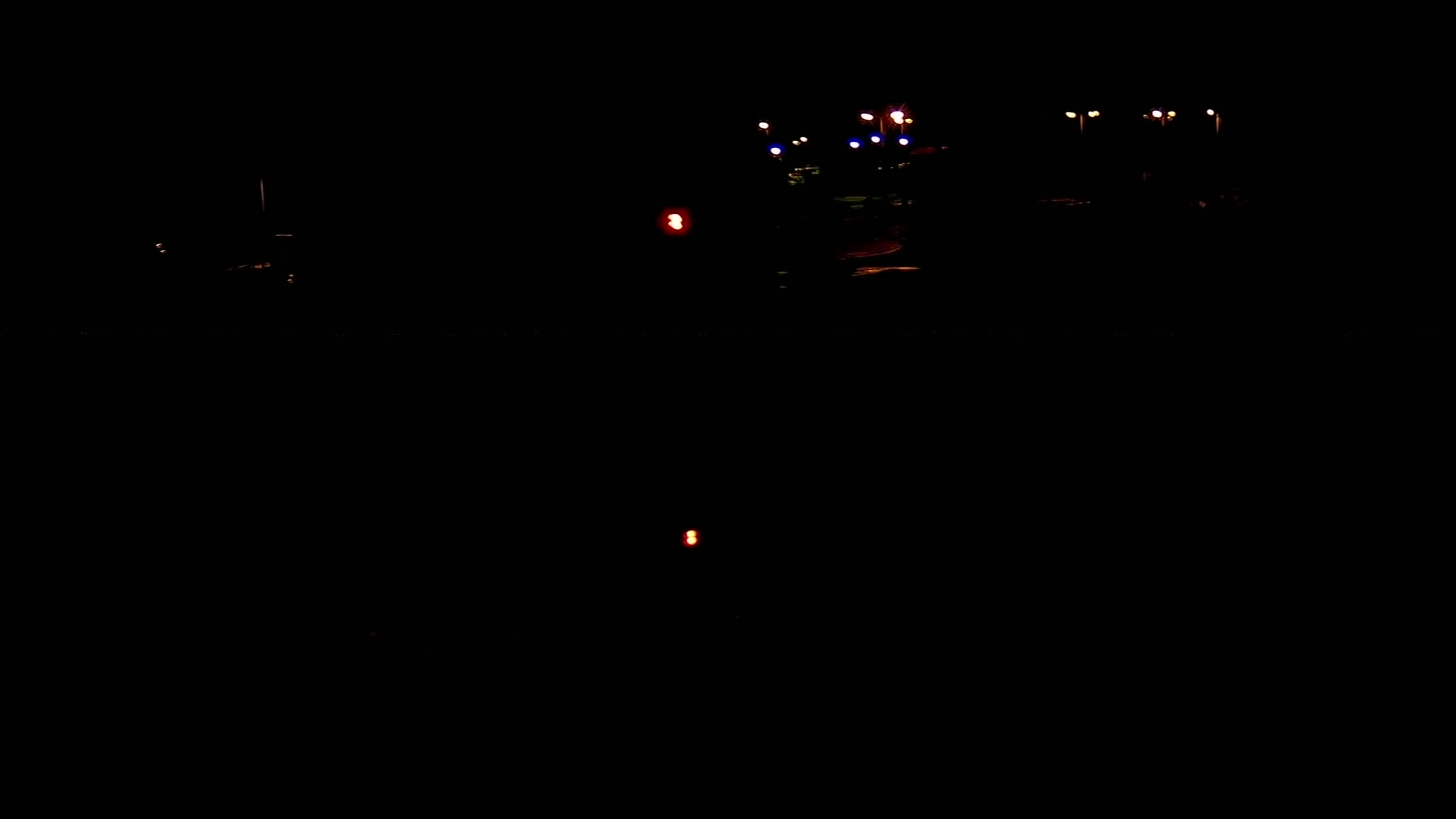 Faintly lit vehicles and streetlights are visible in the dark of night.